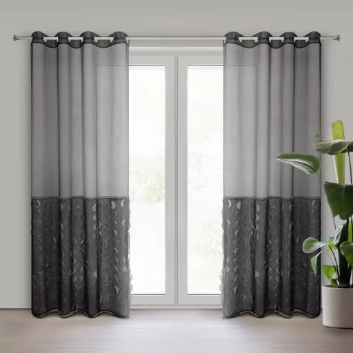 Elegáns grafitszürke voile készfüggöny különleges áttört mintás alsó betéttel. A könnyed fényáteresztő anyag és a modern fémkarikás kialakítással 140X270cm 